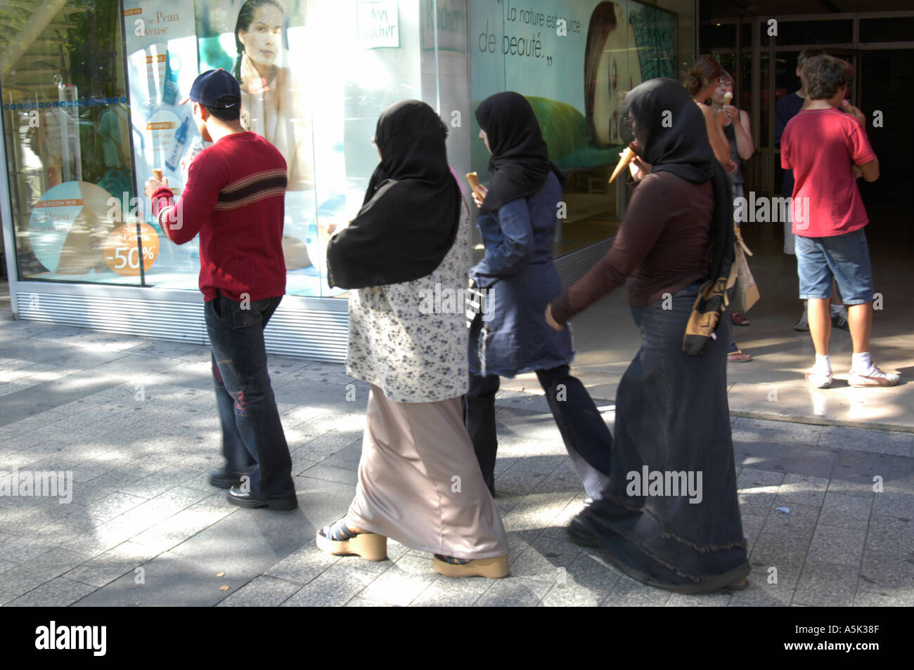 Francia, Parigi. Presenza musulmana sugli Champs Elysée. Giovani donne con uomo porta. Tutti godendo di gelati Foto Stock