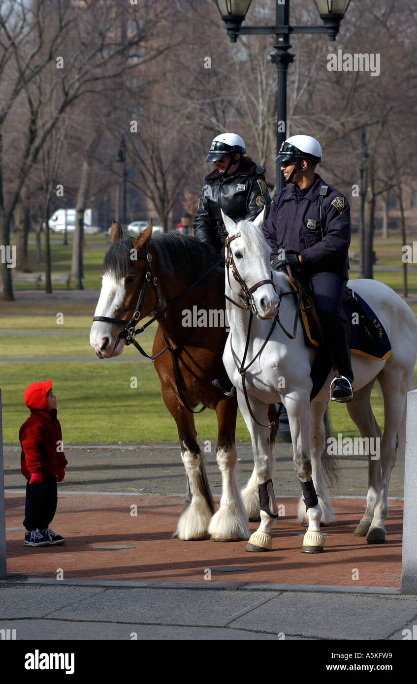 Montato a cavallo di polizia con un bambino ammiratore Foto Stock