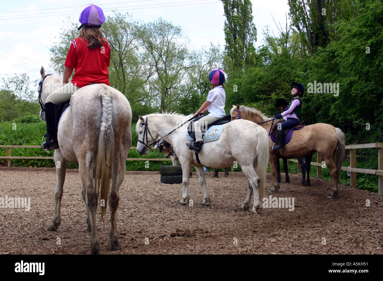 3 ragazze giovani seduti sul pony presso un esterno di una scuola di equitazione Foto Stock