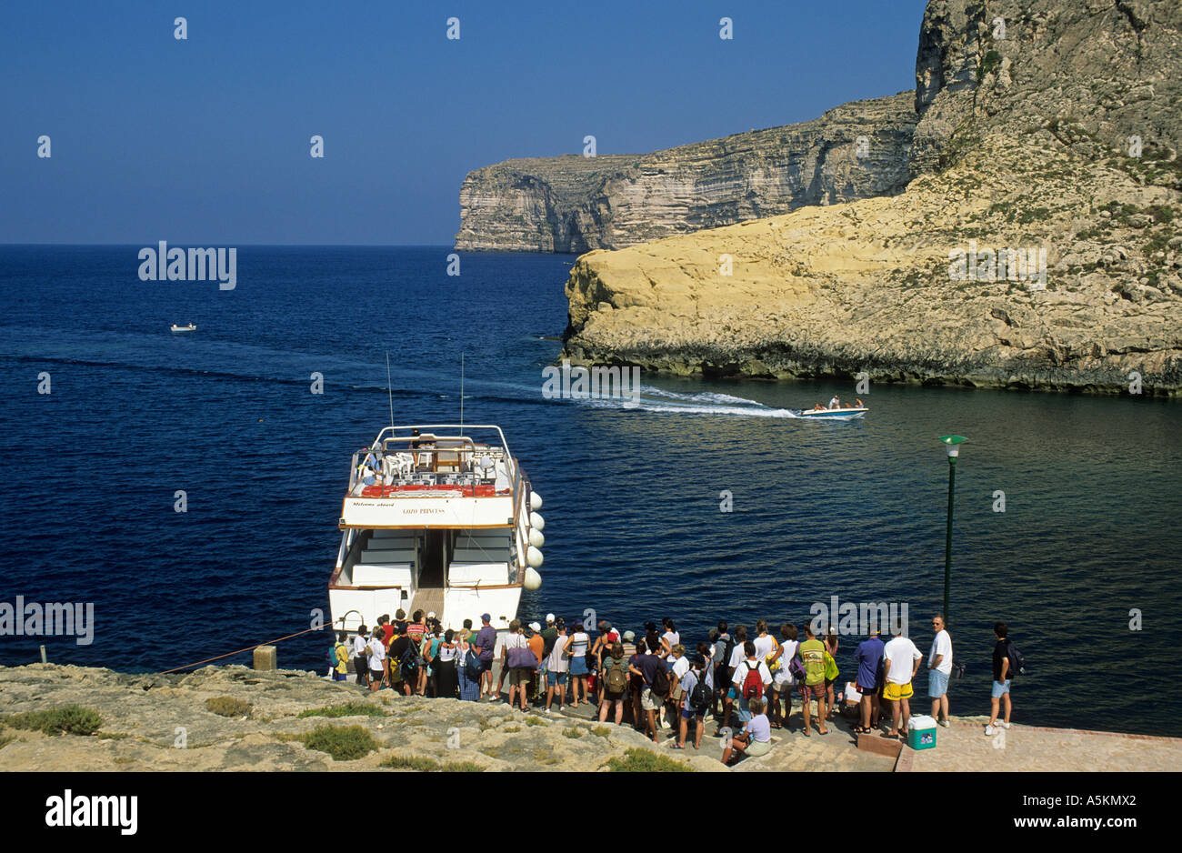 I turisti di salire a bordo di un battello turistico a Xlendi Bay, isola di Gozo, Malta Foto Stock