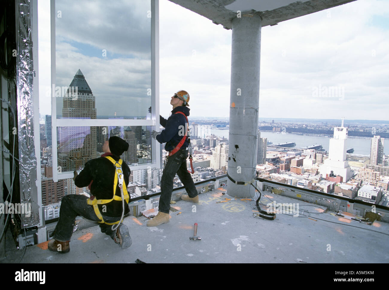 Lavoratori, con cablaggio di sicurezza sganciati, installazione di parete di tamponamento a Random House Building di New York City Foto Stock