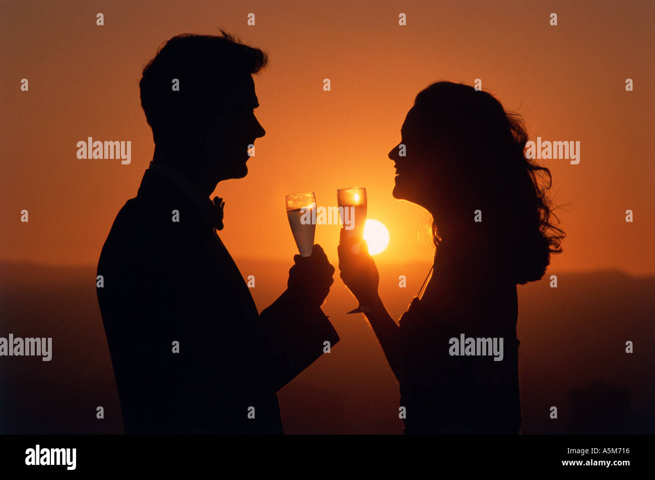 Paio di celebrare la vita l'amore sulla parte superiore di un edificio con champagne durante il tramonto in California Foto Stock