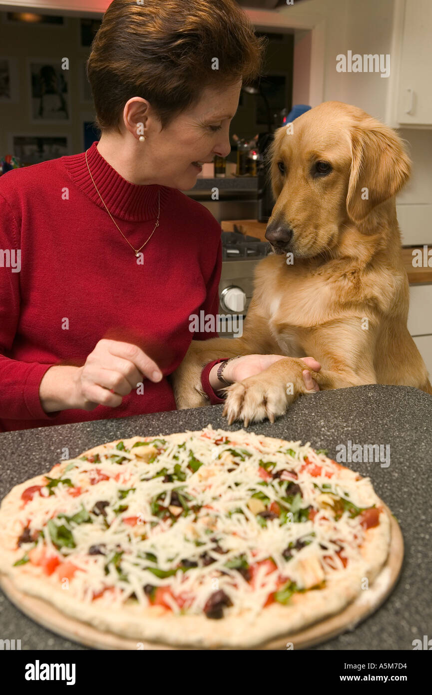 Femmina proprietario di pet con il Golden Retriever in cucina dopo la cottura della pizza Foto Stock