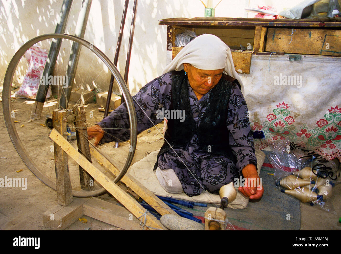 Anziani Uighur donna la filatura filo di seta Foto Stock