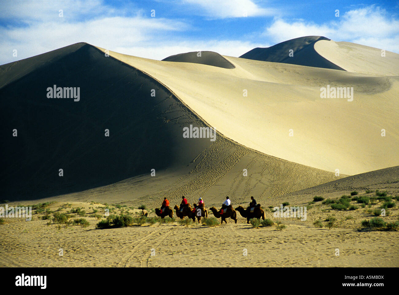 Dunhuang canta Sands dune di montagna con i turisti sul cammello carovana in provincia di Gansu in Cina Foto Stock