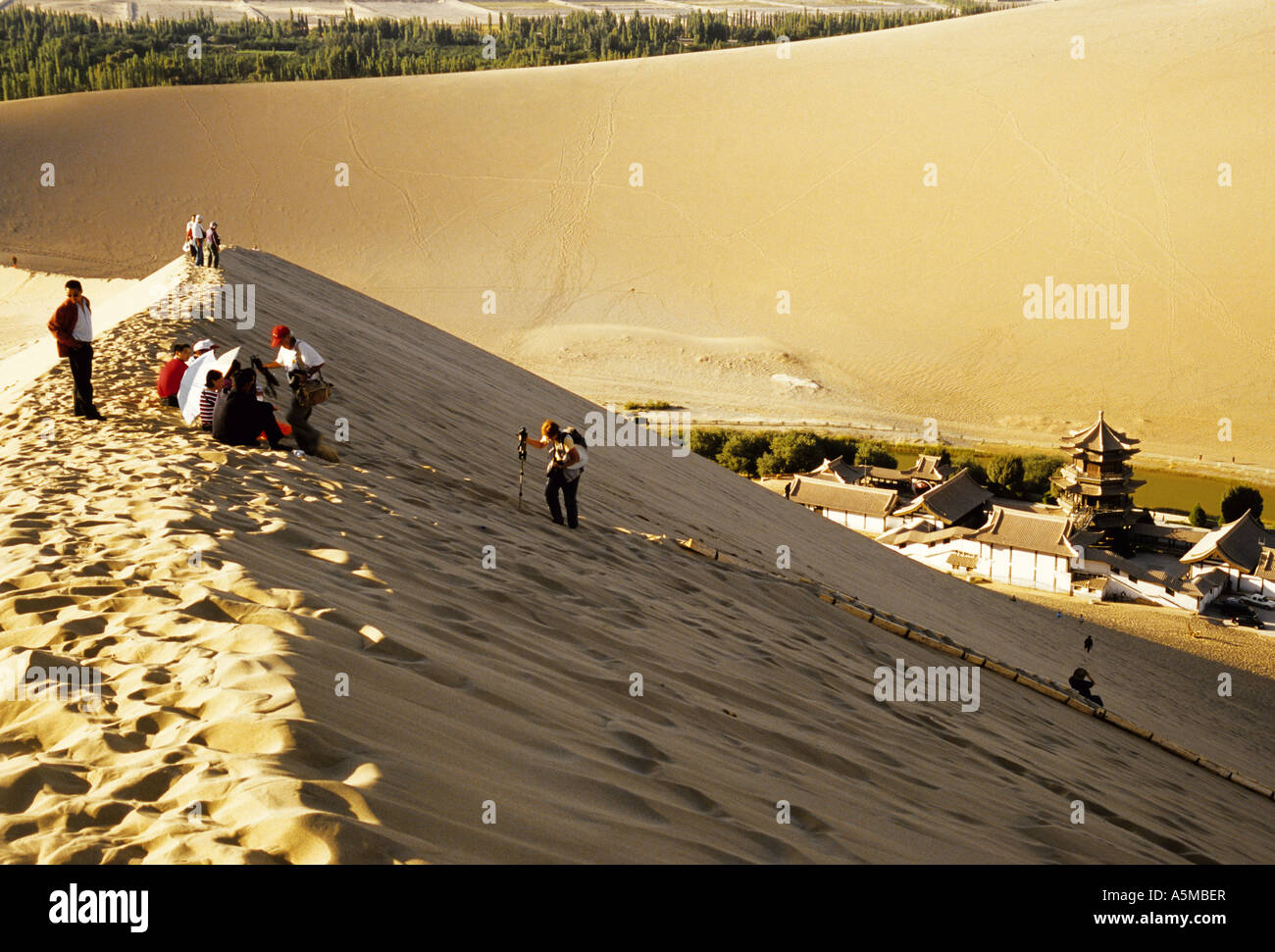 Dunhuang canta Sands montagne con i turisti dune di arrampicata al di sopra di Mezzaluna lago nella provincia di Gansu in Cina Foto Stock