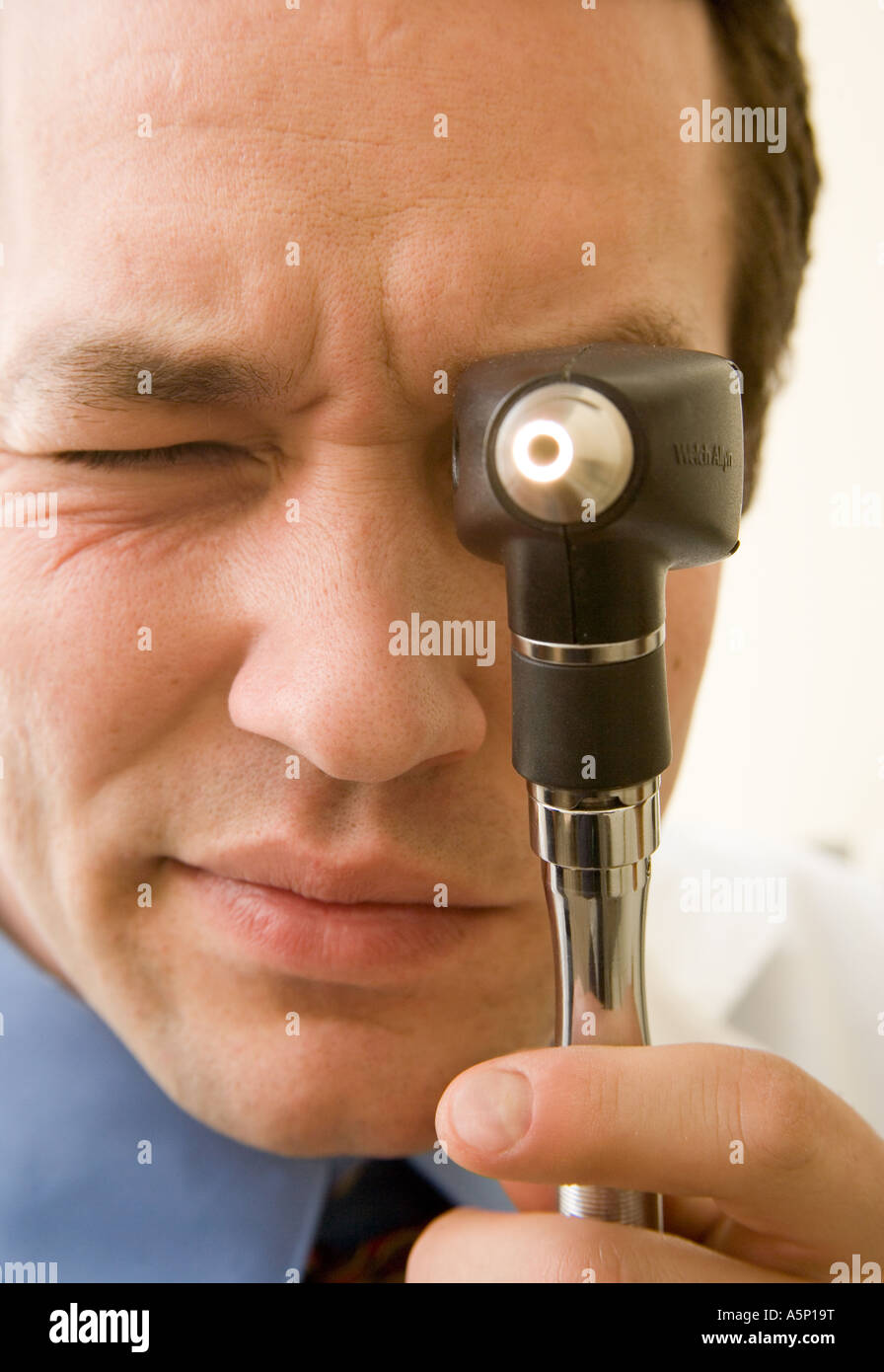 Medico utilizza un otoscopio per visualizzare all'interno dei pazienti orecchio e del naso. Foto Stock