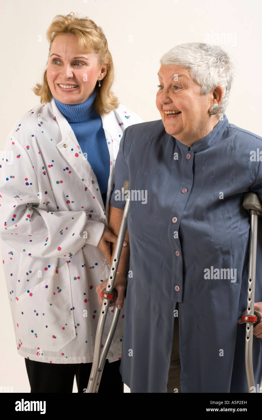 Home Visita Sanitaria infermiere assiste paziente di sesso femminile con le stampelle. Foto Stock