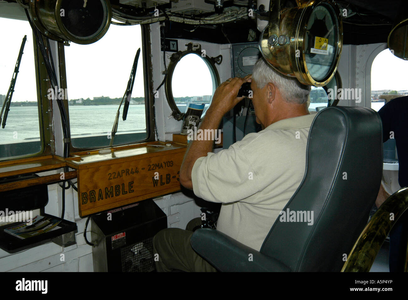 Un Capitano della sua nave sul ponte guardando attraverso il binocolo. Foto Stock