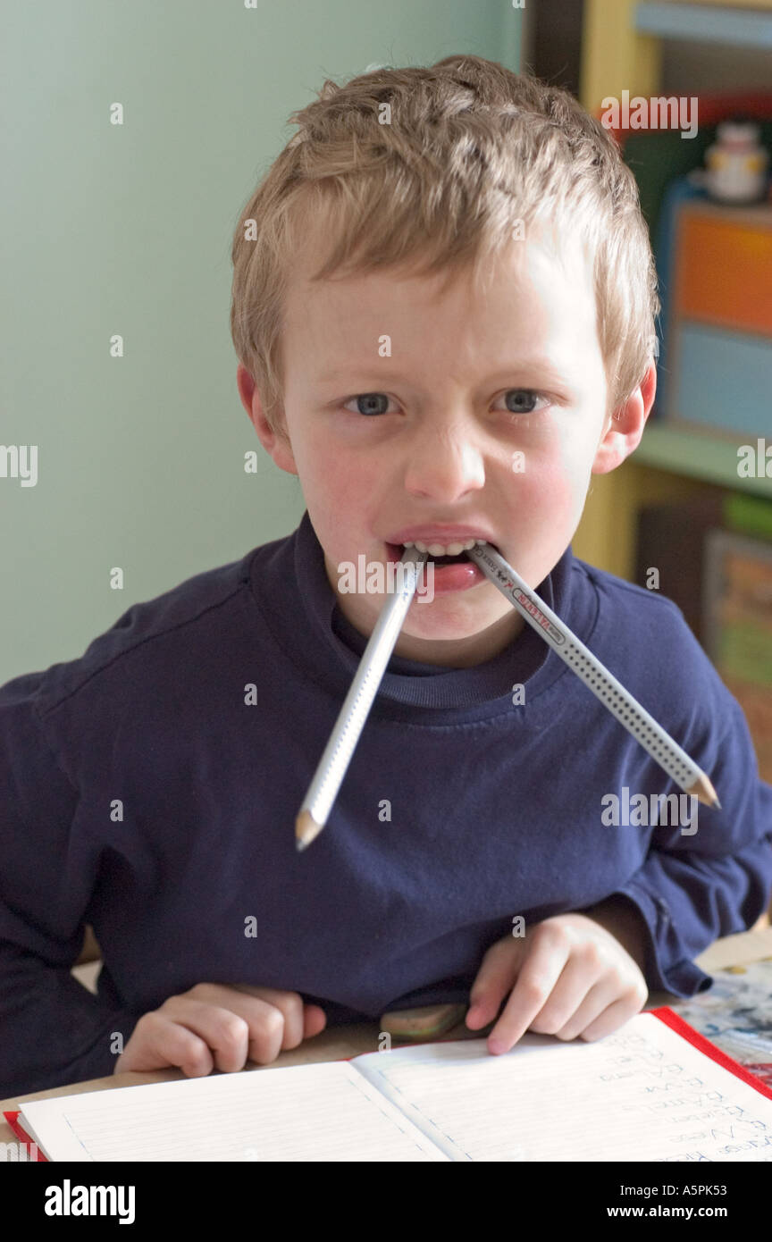 Signor sei anno vecchio ragazzo seduto alla scrivania facendo i compiti di scuola Foto Stock