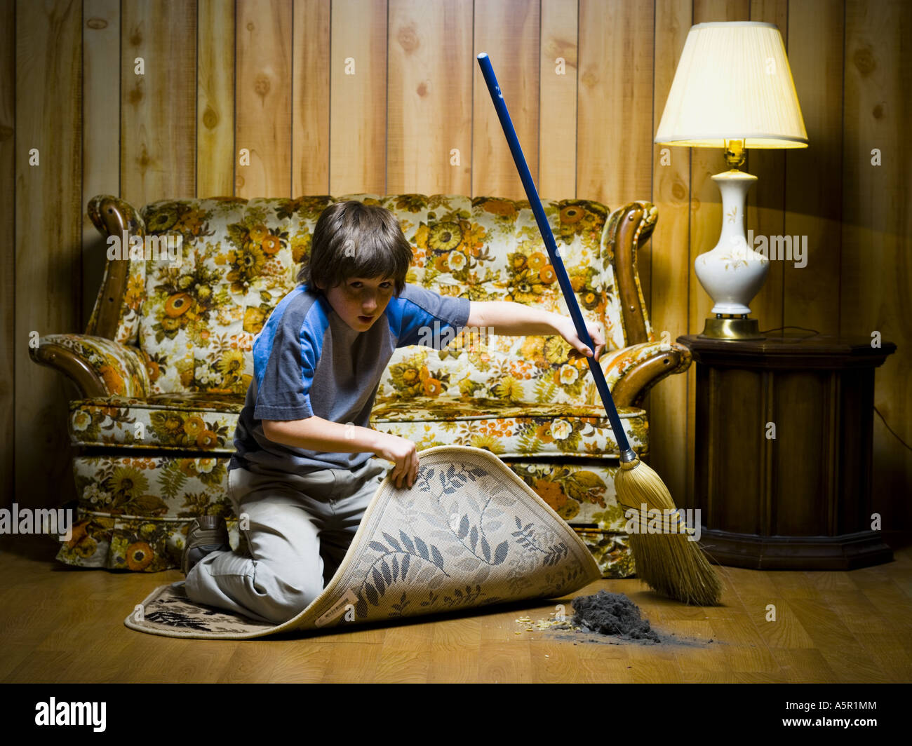 Ragazzo spazzare la sporcizia sotto la coperta Foto Stock