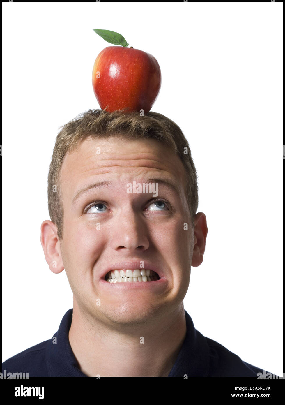 Close up di un giovane uomo stringendo i denti con un Apple sulla sua testa Foto Stock