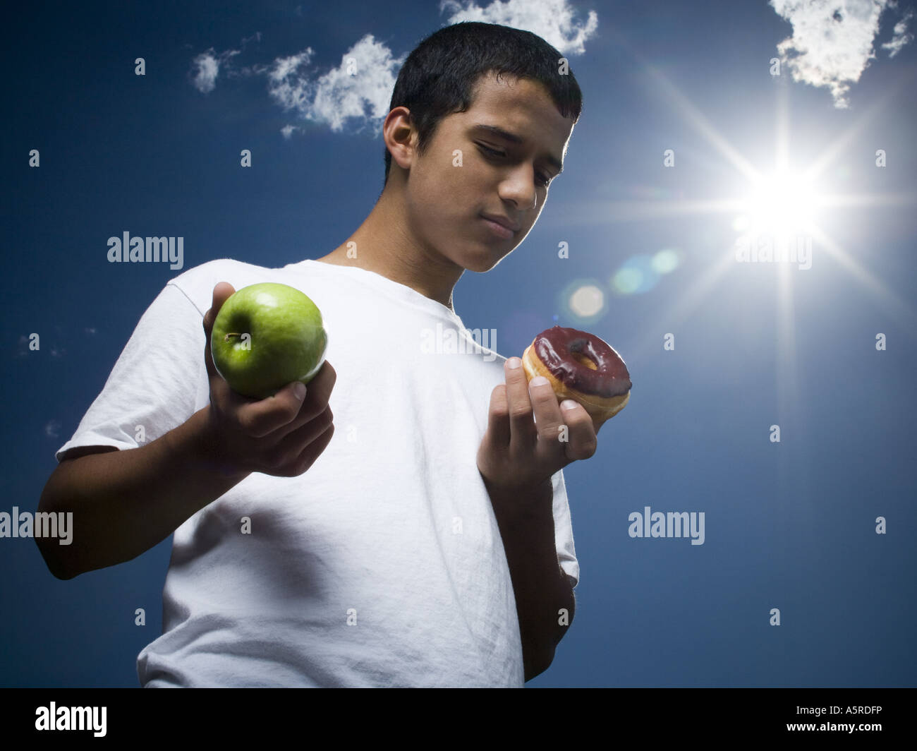 Basso angolo di visione di un ragazzo adolescente tenendo un Apple e una ciambella Foto Stock