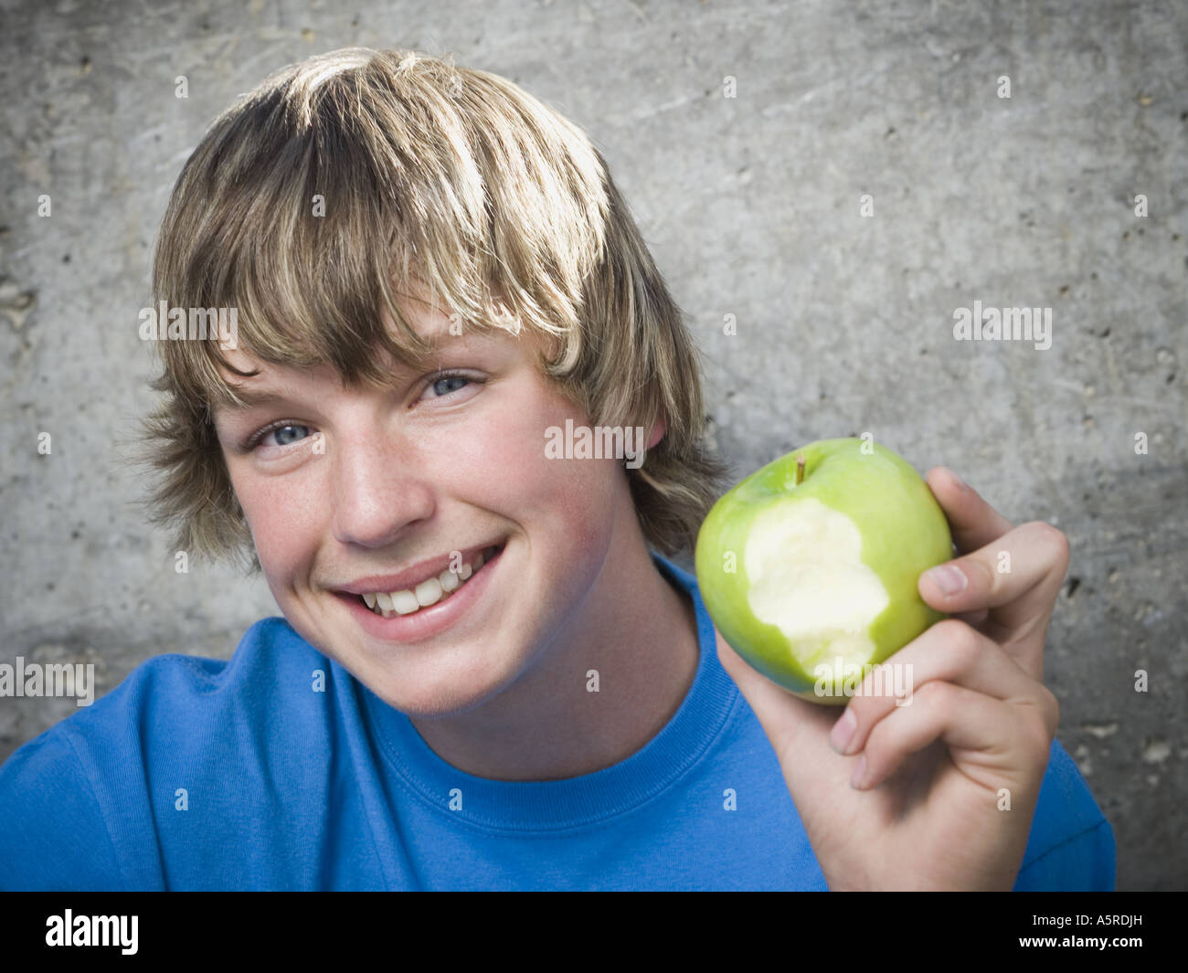 Ritratto di un ragazzo adolescente tenendo un apple e guardando allegro Foto Stock