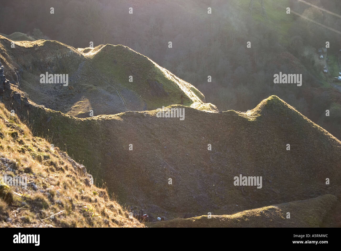 Il minerale di ferro di cumuli di scorie sulla scarpata Llangattock, sopra Clydach Gorge, se il Galles stagliano contro il sole di setting Foto Stock