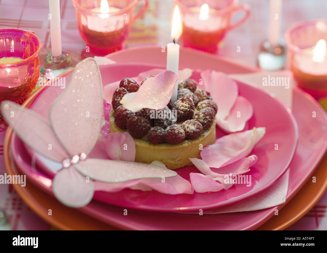 Lampone pasticceria su lastra decorata con petali di rosa e candele Foto Stock