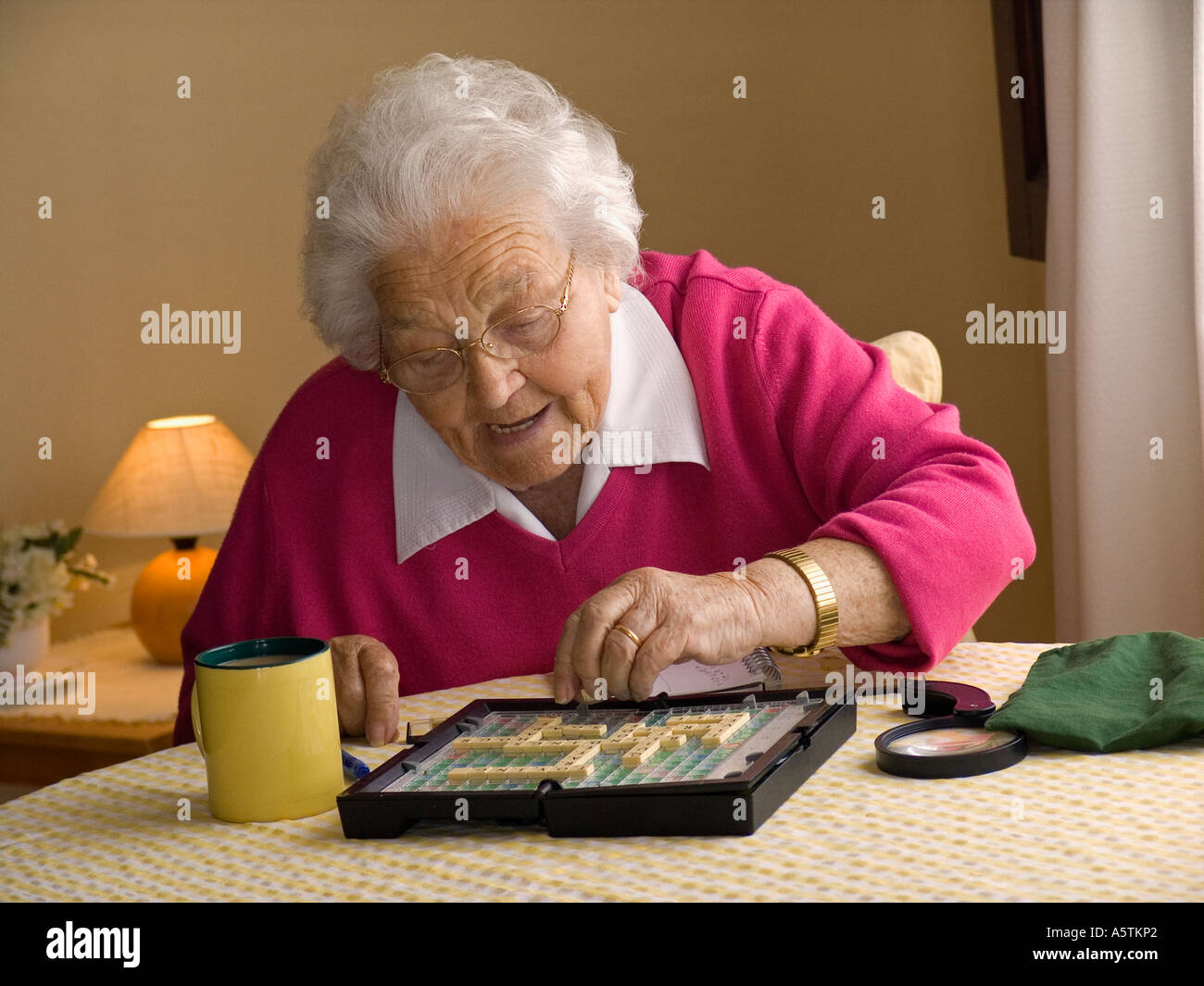 Anziana signora indipendente gode di un solitario gioco di Scrabble home Foto Stock