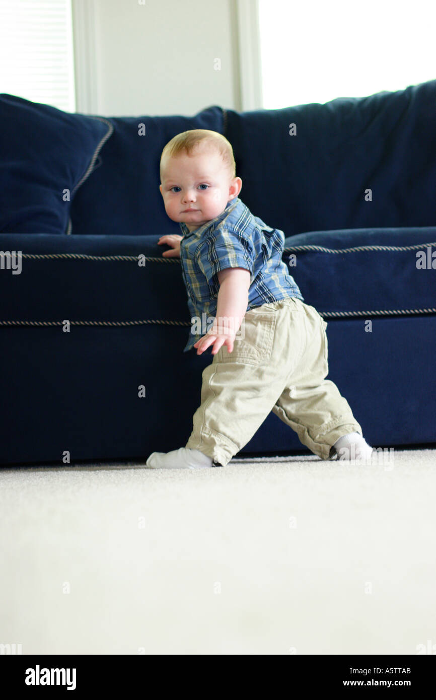 9 mese old boy in piedi tenendo premuto sul lettino Foto Stock