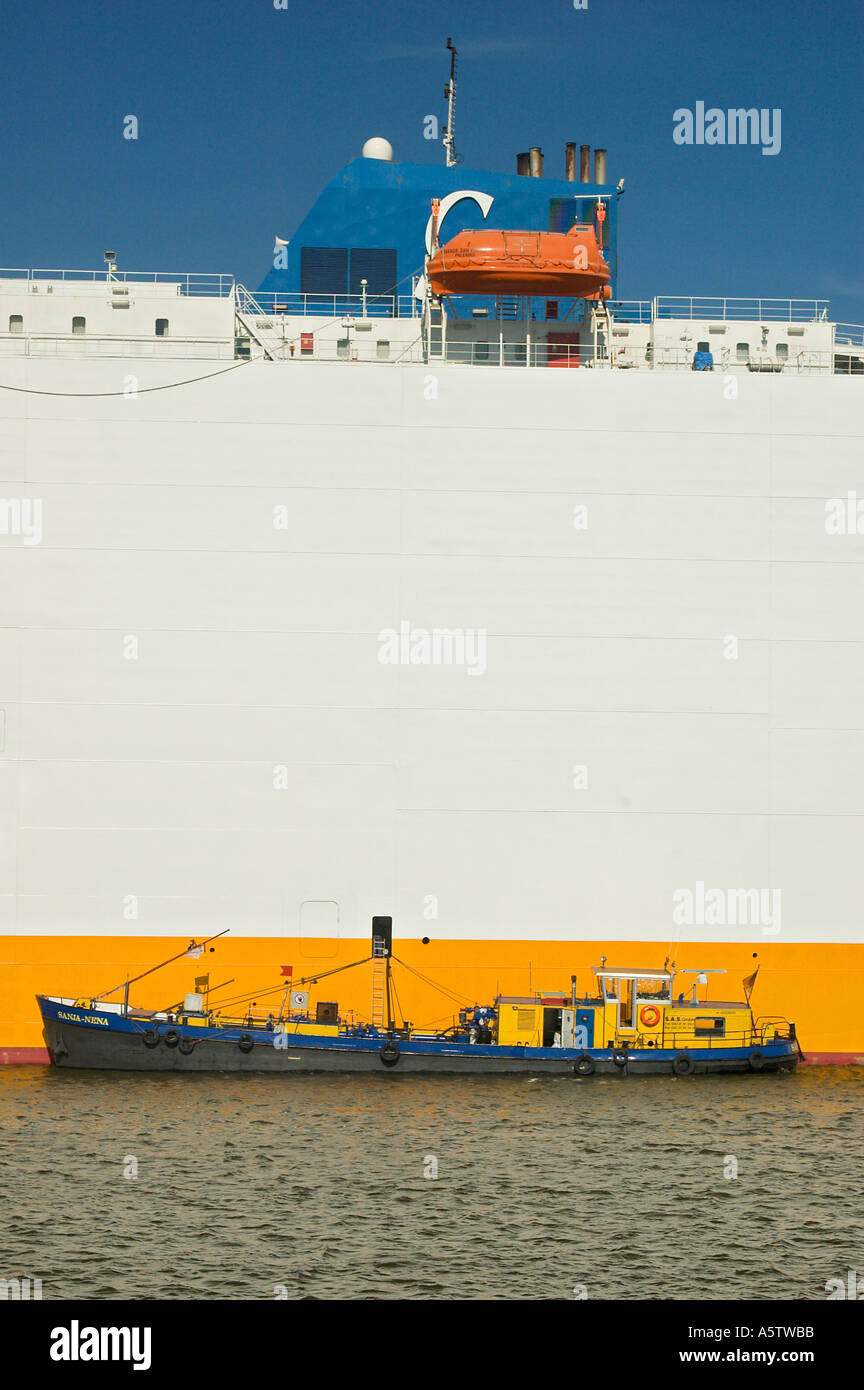 Piccola imbarcazione a fronte di un contenitore grande nave al porto di Amburgo Germania Foto Stock