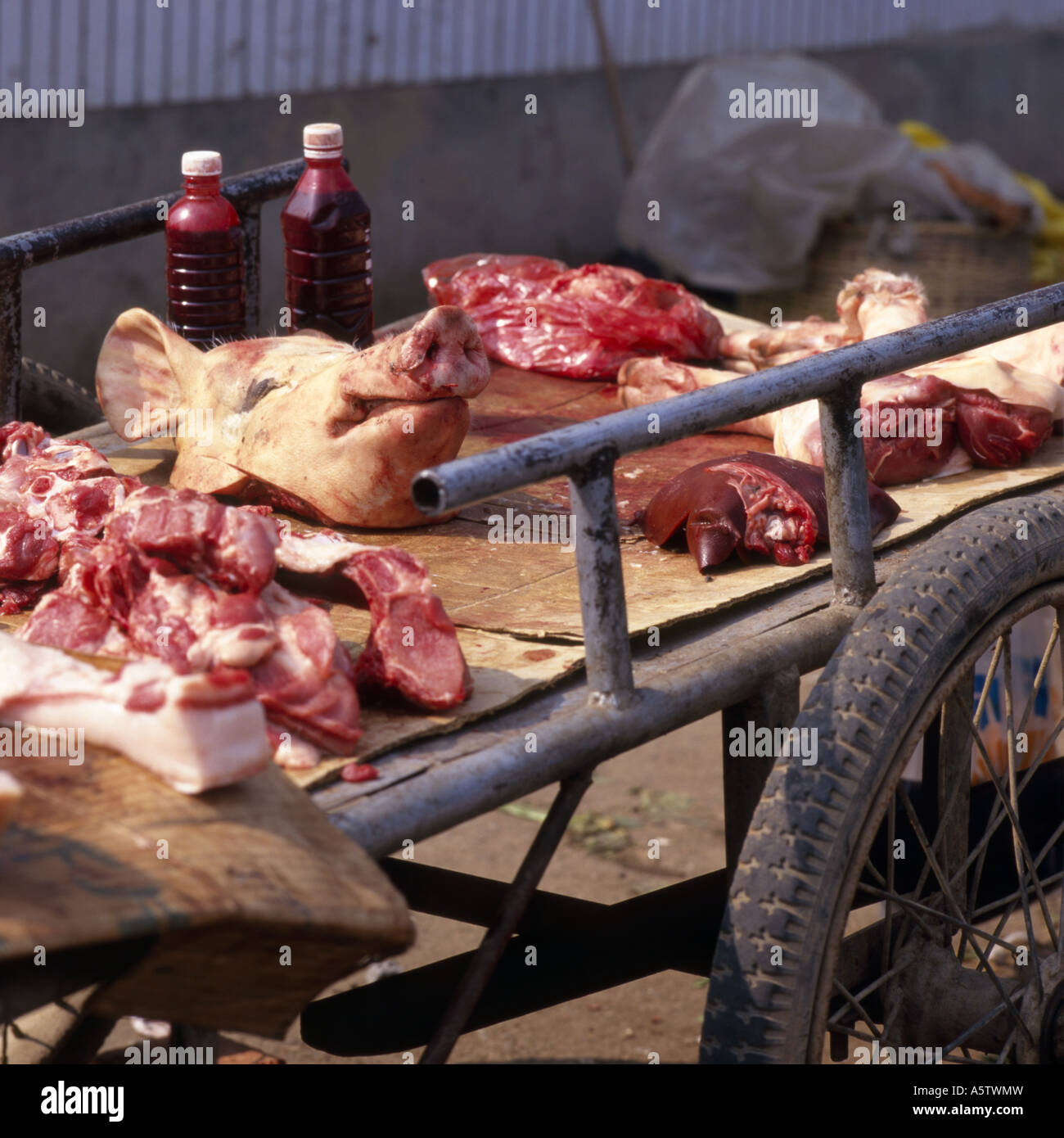 Carriola in legno tenendo un suini faccia,bottiglie di sangue di suini e di carni suine,in vendita nel mercato,nella provincia dello Yunnan,Cina. Foto Stock