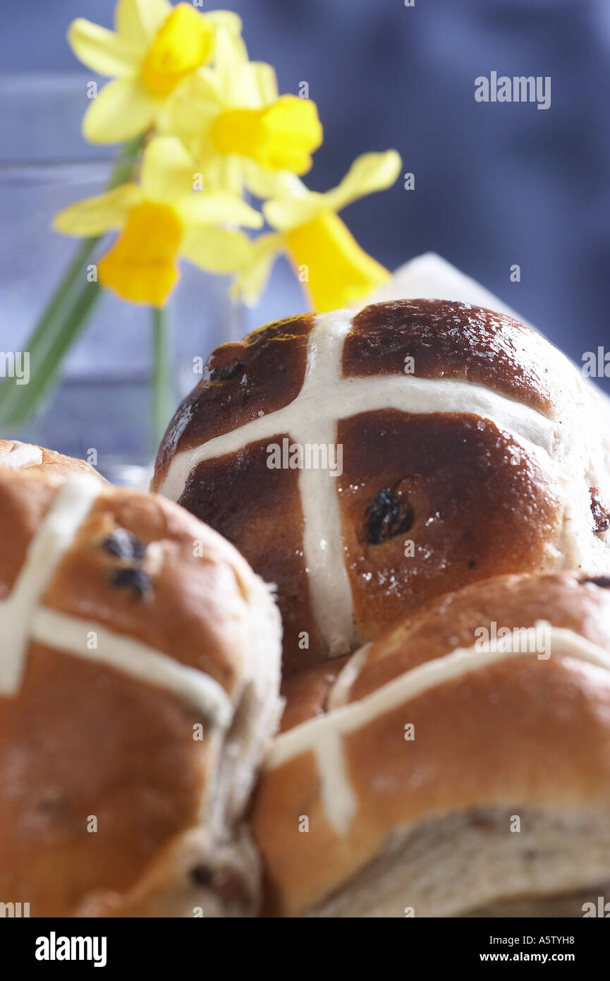 Hots ciambelle a croce sul tavolo per la colazione di Pasqua con fiori Foto Stock