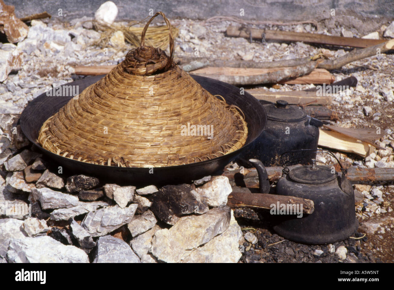 Cono di vimini a copertura di wok sul fuoco aperto,annerite bollitori,su terreni incolti,il sud-ovest della Cina. Foto Stock