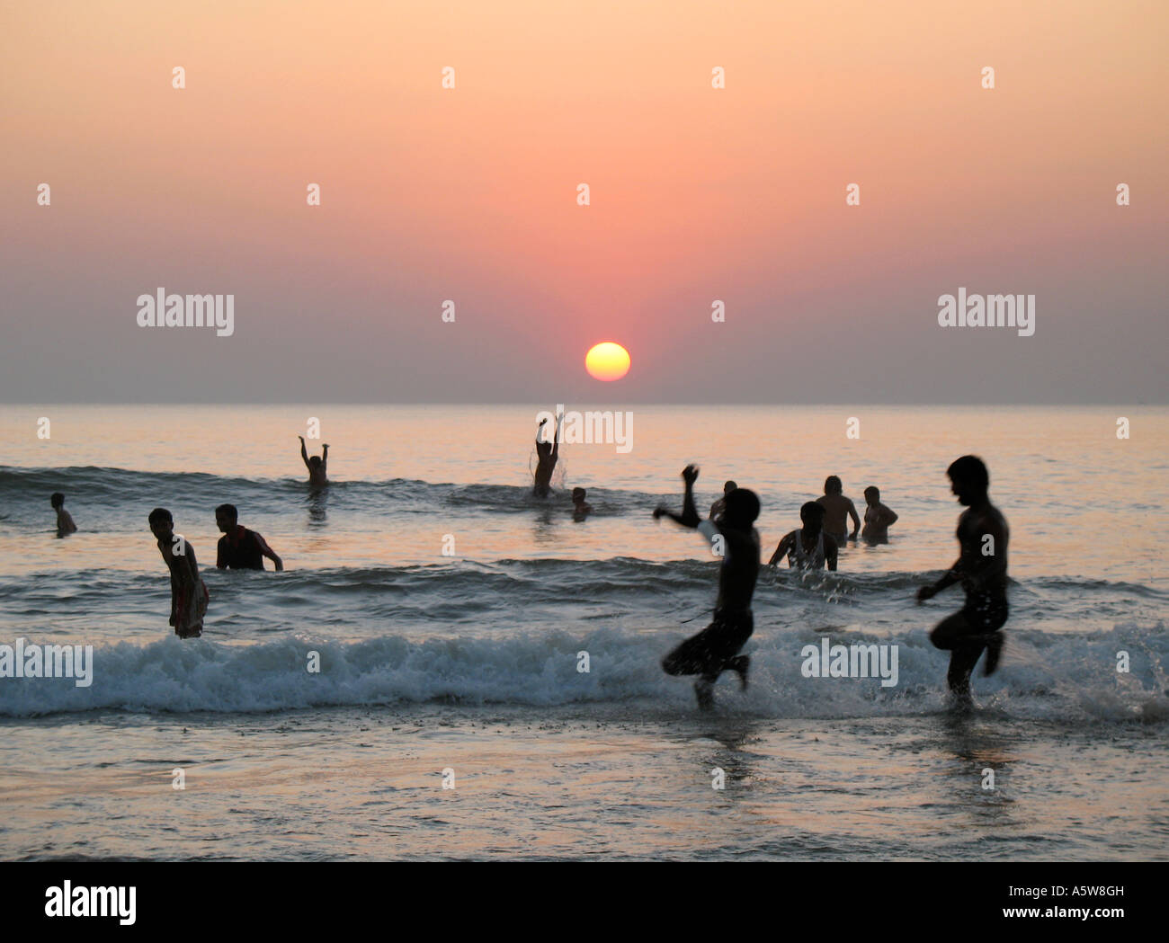 Gli indiani di nuoto in mare in Gokarna India del Sud al tramonto Foto Stock