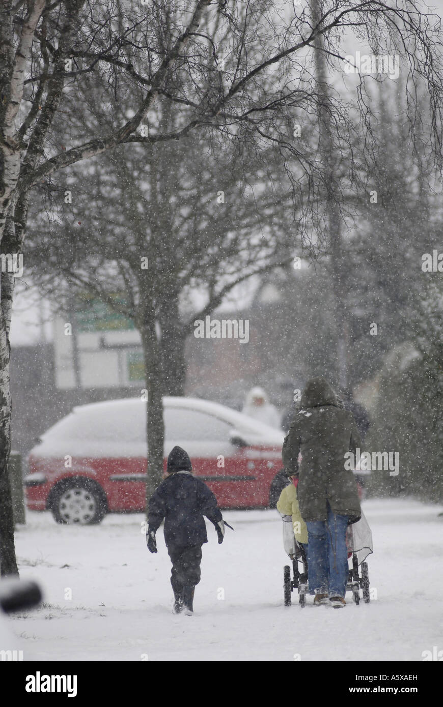 Madre spingendo il suo bambino un passeggino nella neve Inghilterra Foto Stock