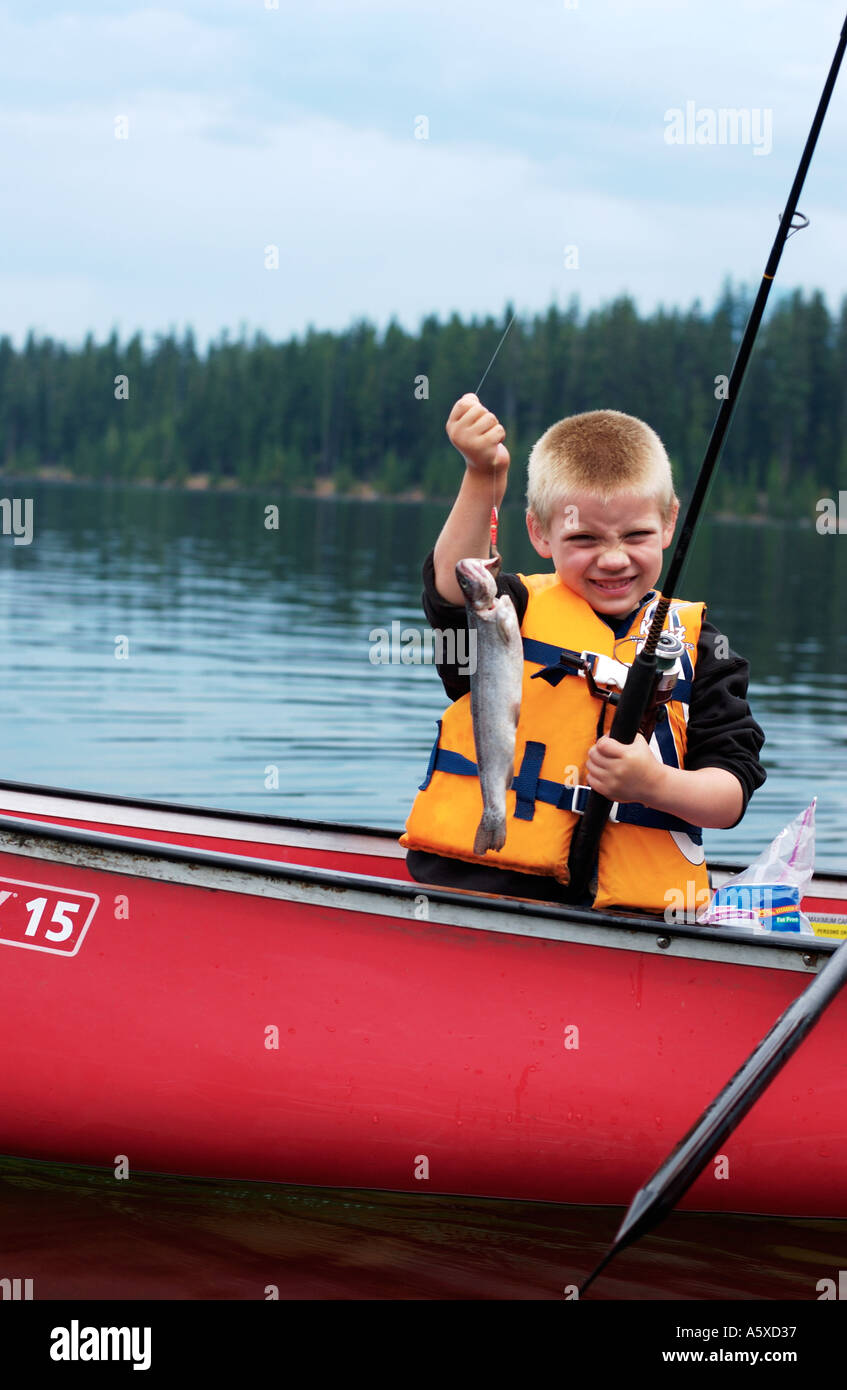 5 anno vecchio ragazzo in rosso canoa tenendo il pesce Foto Stock