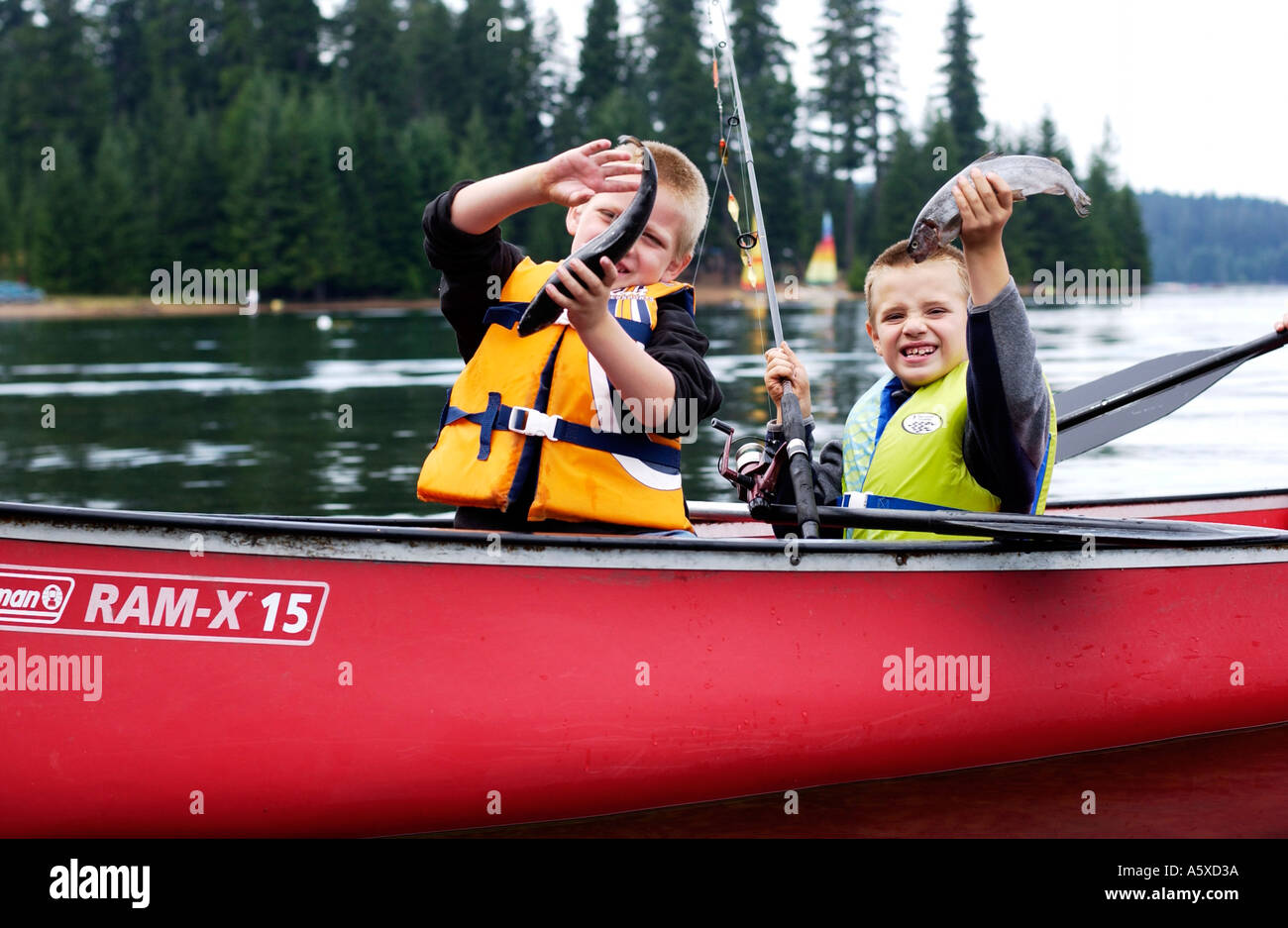 5 e 6 anno vecchio cugini in rosso canoa tenendo il pesce Foto Stock