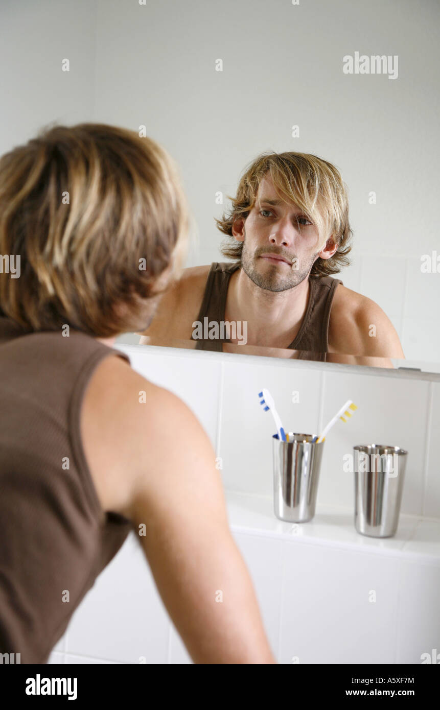 Giovane uomo guardando in uno specchio in bagno vicino fino Foto Stock
