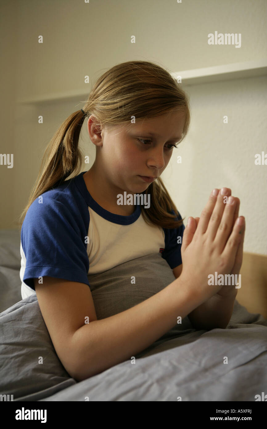 Ragazza pregare prima di andare a dormire vicino fino Foto Stock