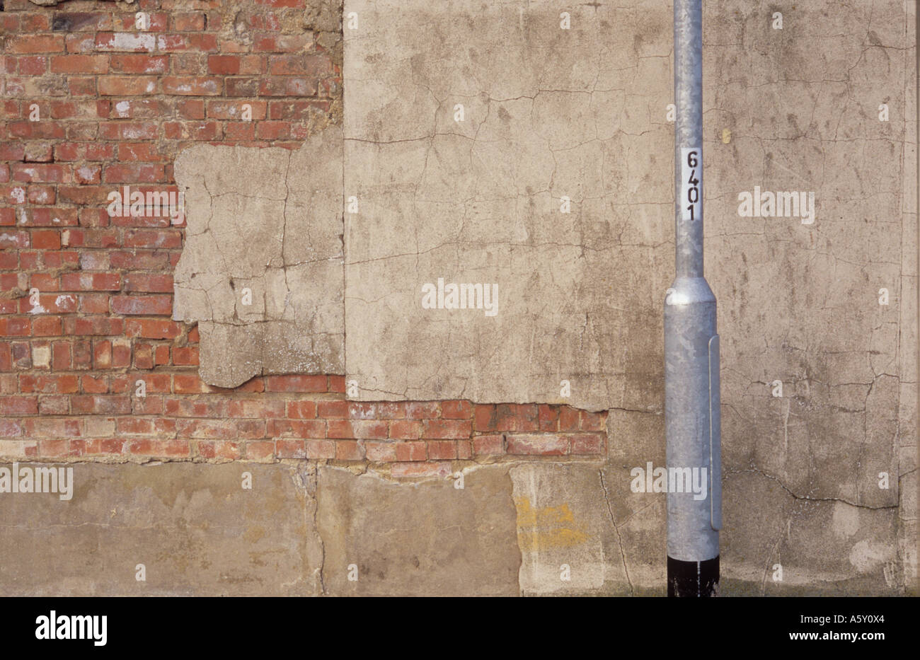 Dettaglio di un argento lampada posta di fronte a un muro di mattoni esposti a causa di grandi pezzi mancanti del rendering di cemento Foto Stock