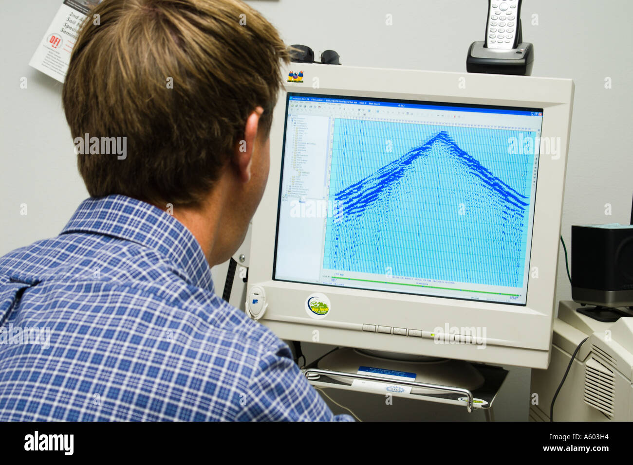 Geophysicist maschio lavora al computer con record di sismica sullo schermo Foto Stock