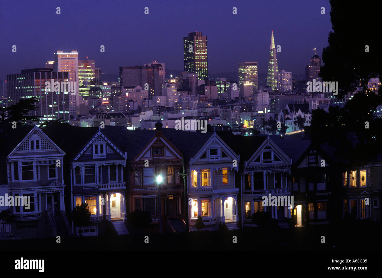 California San Francisco vista serale di cartolina fila di case in stile vittoriano su Alamo Square e skyline del centro Foto Stock