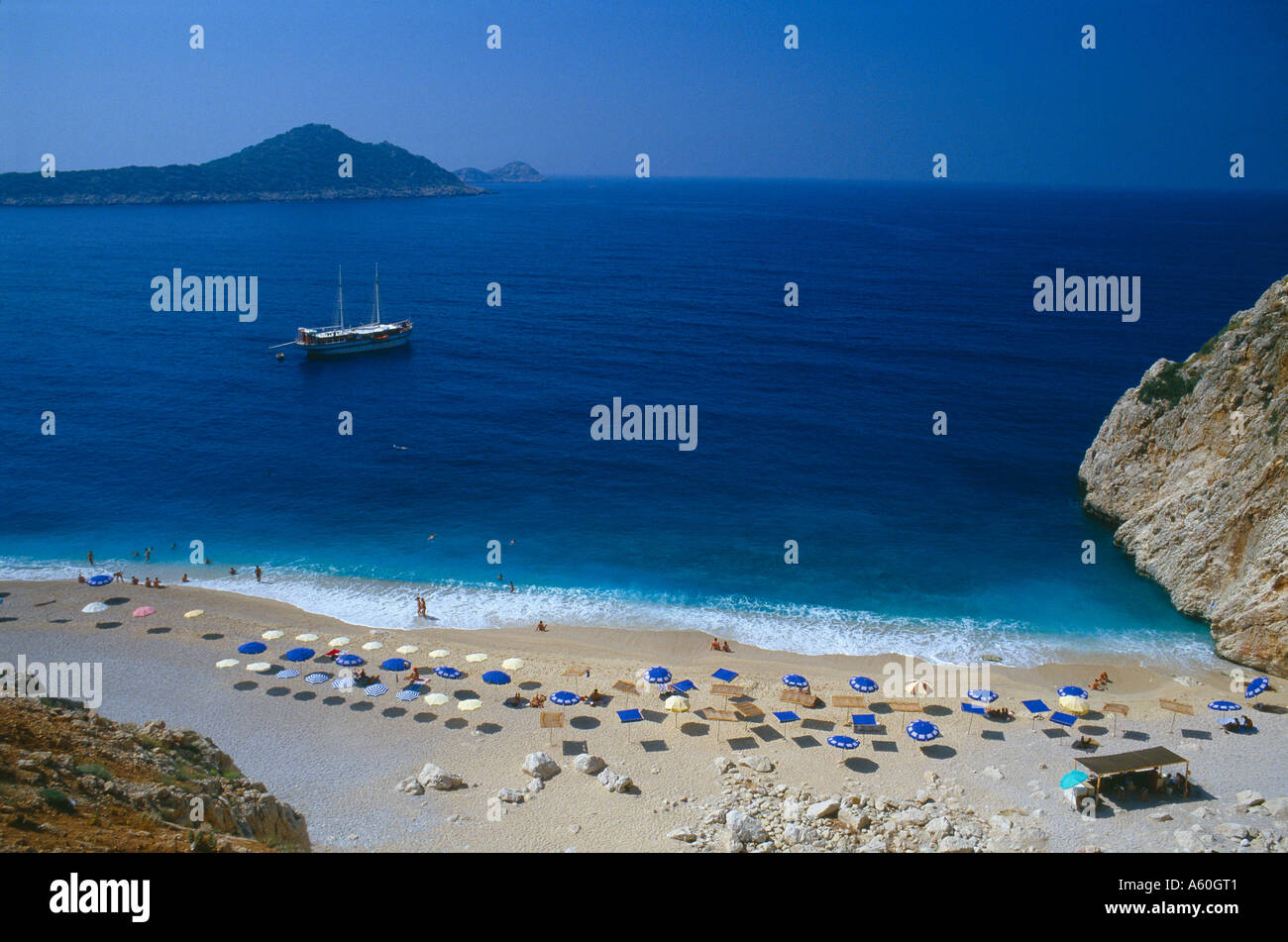 Kaputas spiaggia con ombrelloni e barca ormeggiata al largo della costa del sud nr Kas Turchia Foto Stock