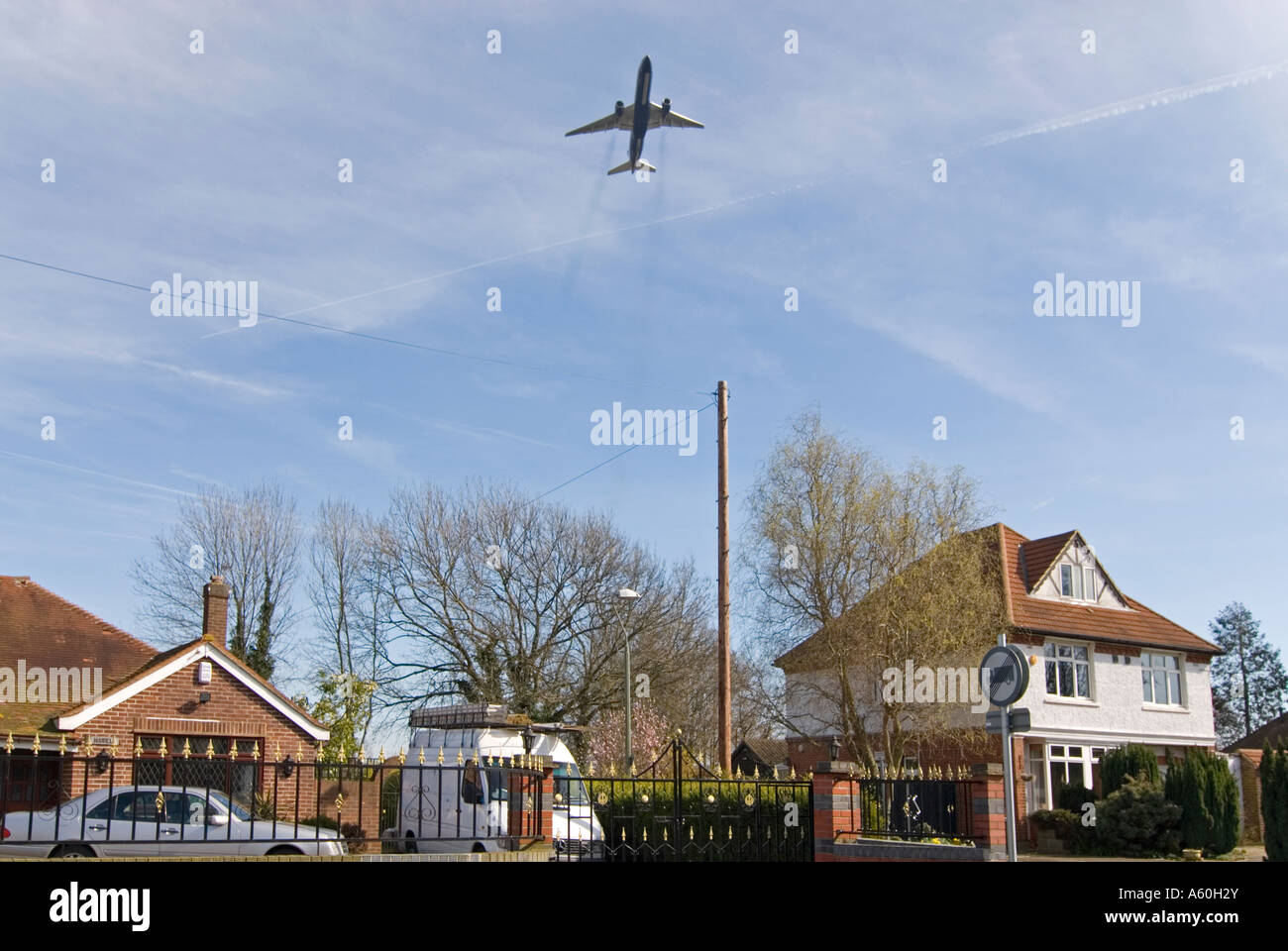 Vista orizzontale di aeromobili in fase di decollo dall'aeroporto di Heathrow, volando a bassa quota sopra case residenziali contro un cielo blu. Foto Stock