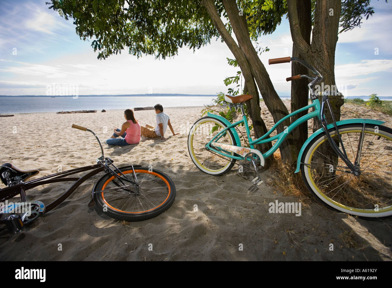Pacific Islander giovane seduto sulla spiaggia con biciclette Foto Stock
