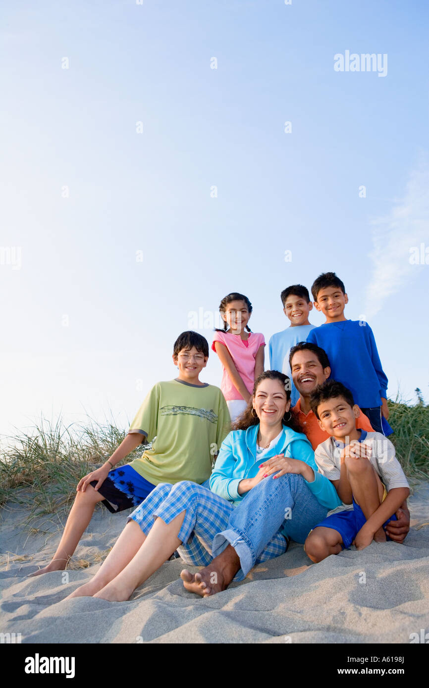 Ritratto di famiglia ispanica seduto sulla spiaggia Foto Stock