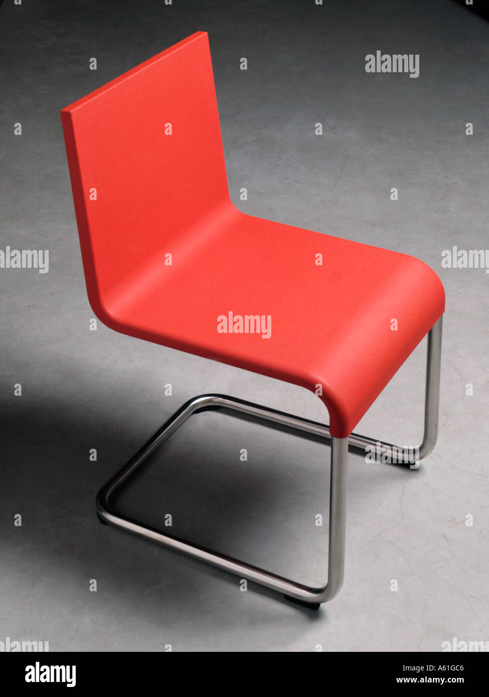 Moderno rosso in plastica sedia cucina su un pavimento di calcestruzzo design by designer olandese Maarten van Severen Foto Stock