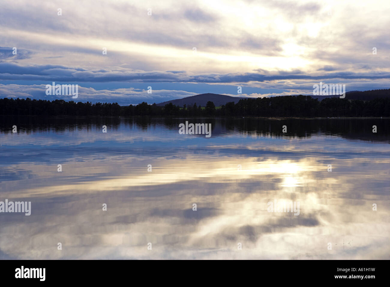 Immagine di panorama di un tramonto in inverno sul Loch di Skene, Aberdeenshire con riflessi sull'acqua calma. Foto Stock