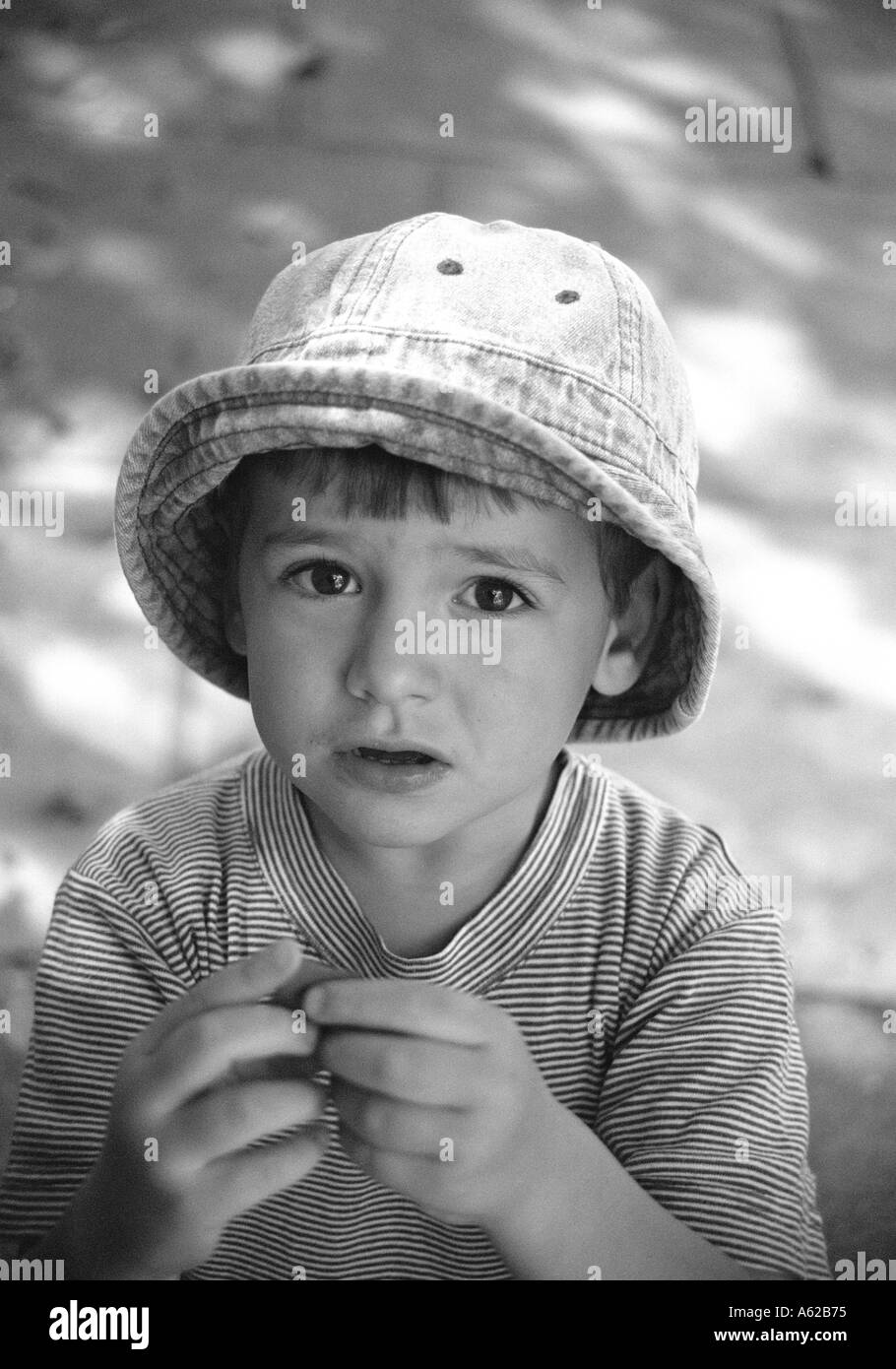Fanciullo in hat e stripey t shirt cercando nervosamente alla fotocamera Foto Stock