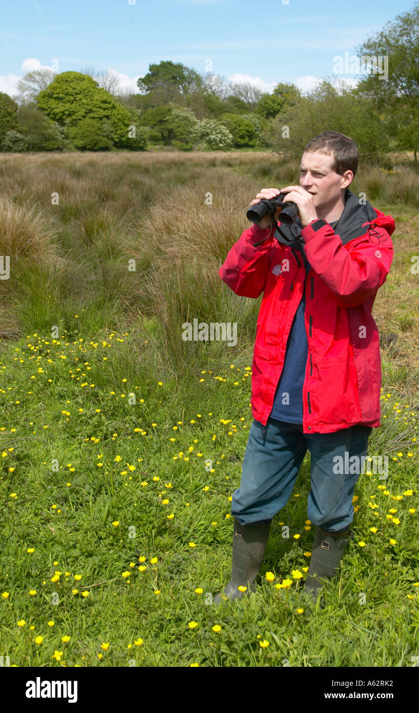 L'uomo birding guardando ad Heysham Moss riserva naturale con la giacca rossa Foto Stock