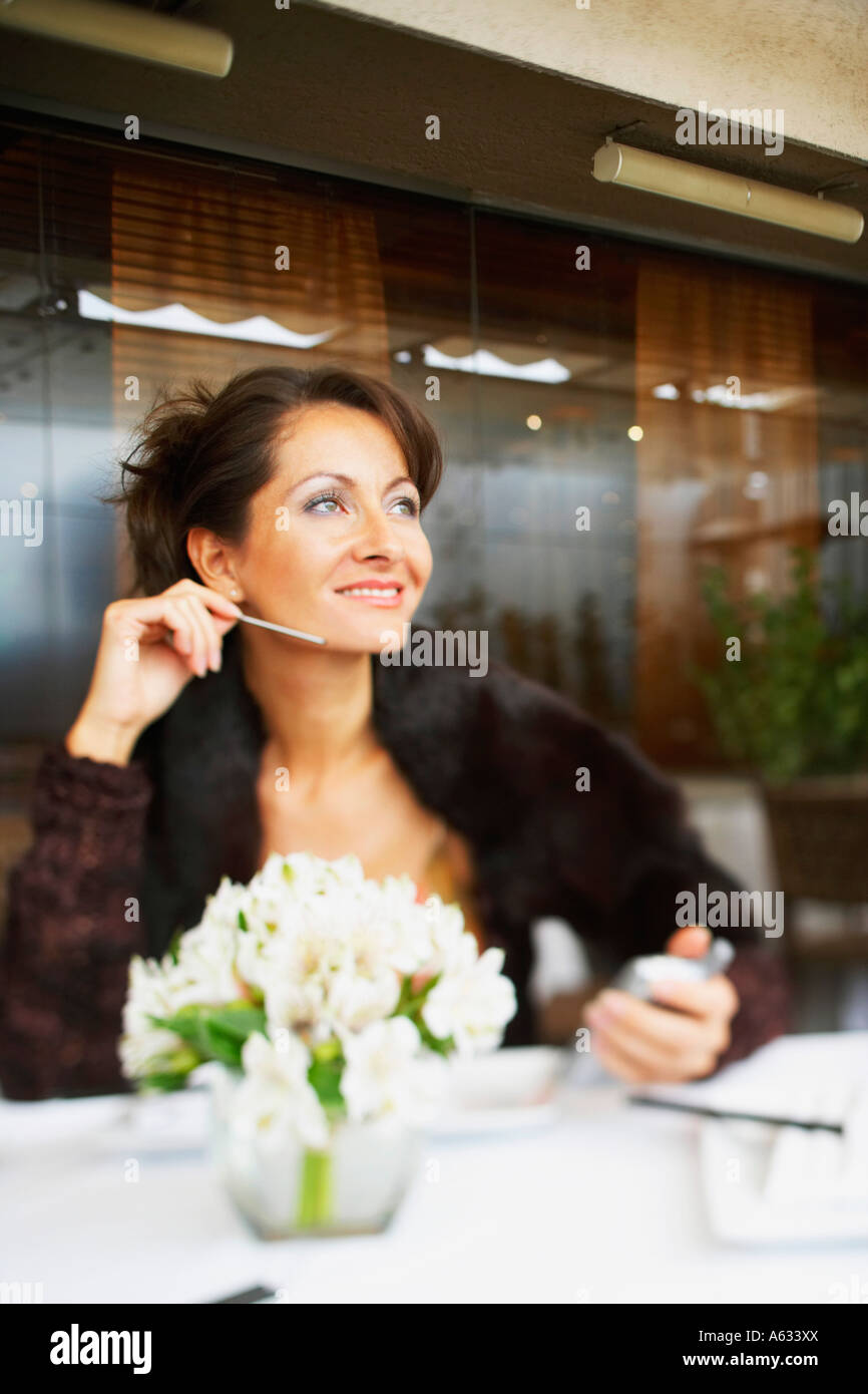 Metà donna adulta seduto in un ristorante con un assistente di dati personale Foto Stock