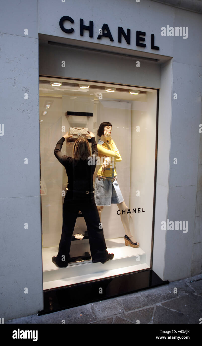 Un negozio assistente presso Chanel a Venezia Italia organizza la finestra di visualizzazione Foto Stock