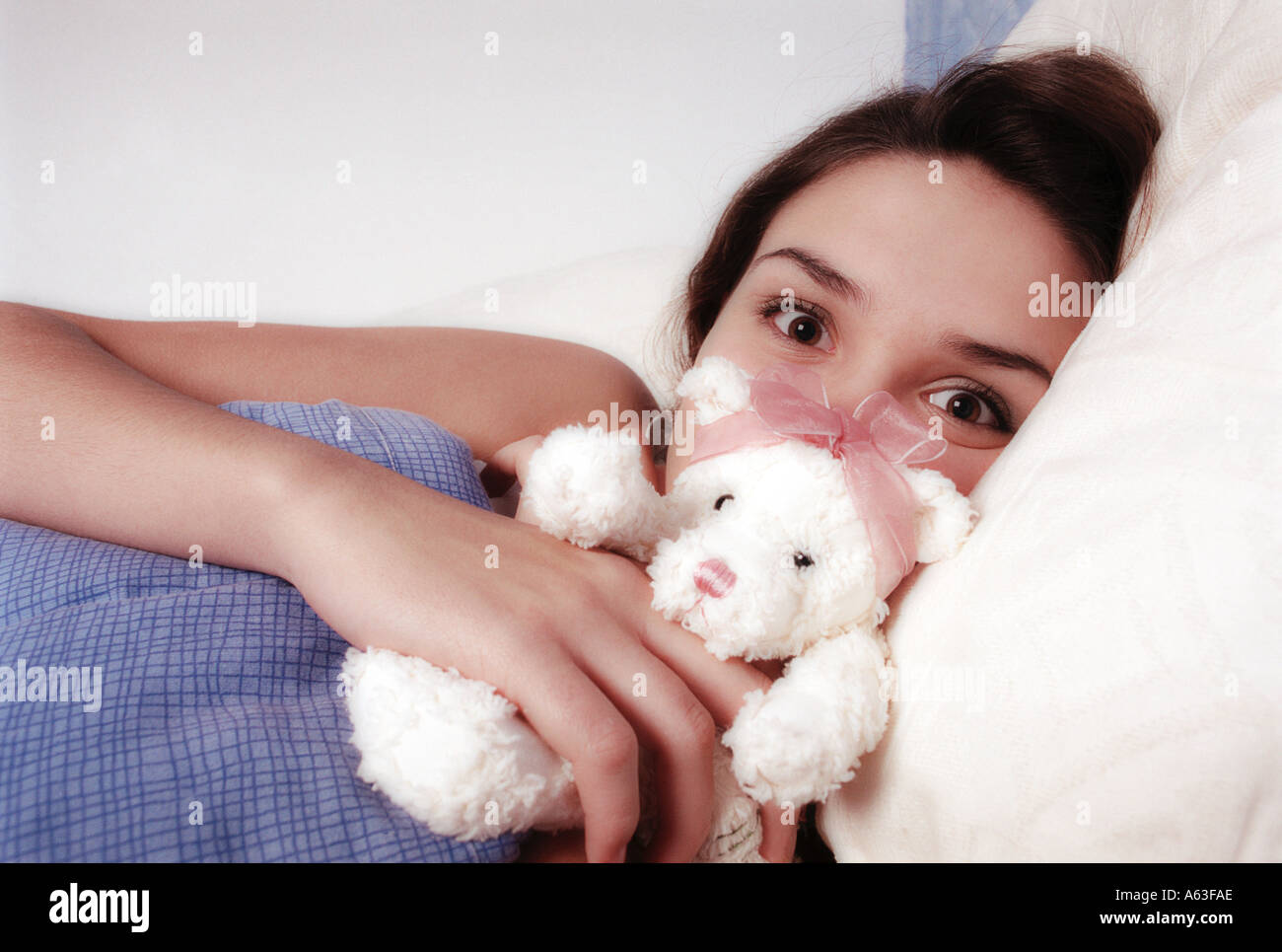 Ragazza adolescente cuddling un orsetto a letto Foto Stock