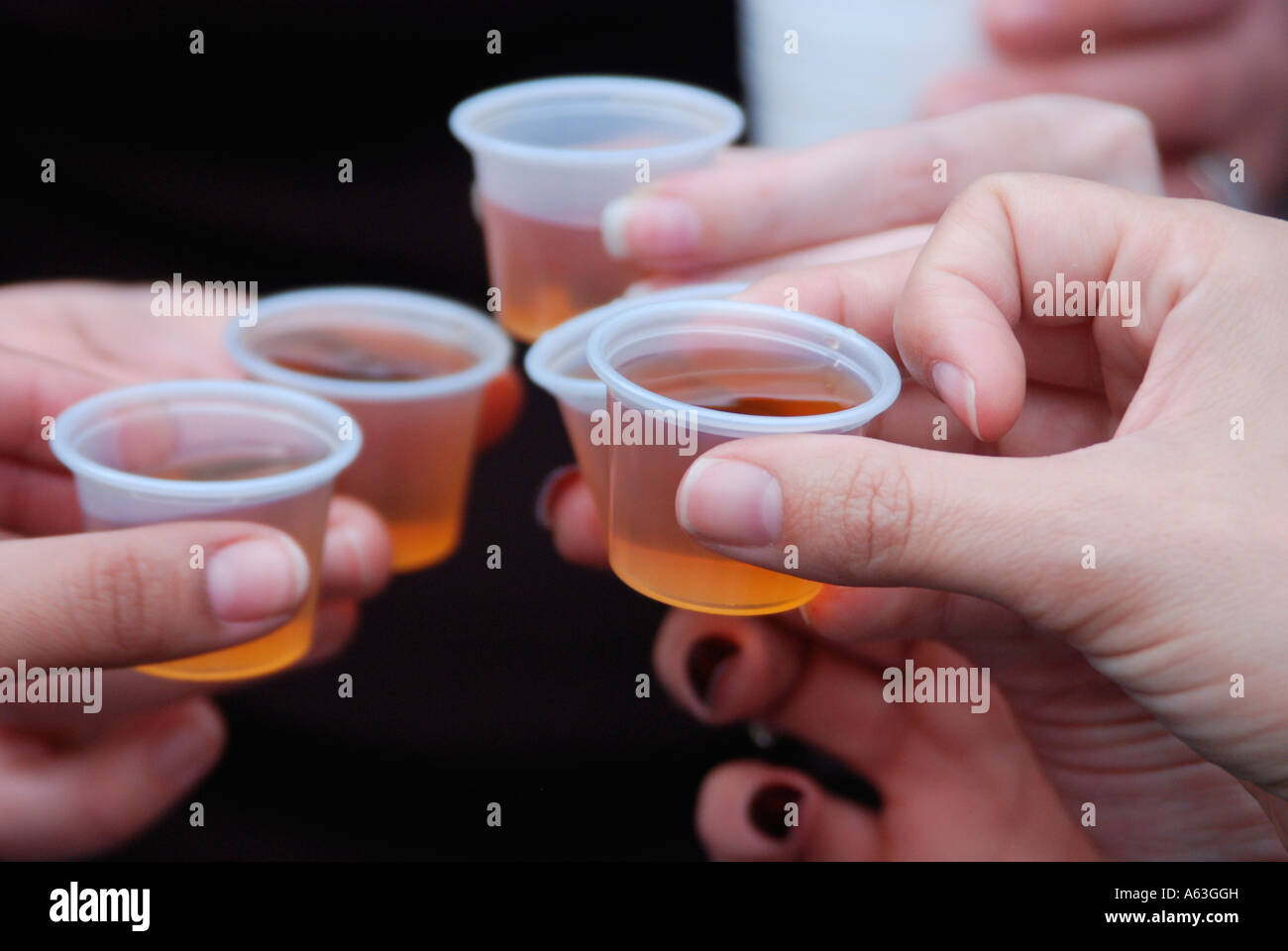 Dettaglio delle mani che tengono la gelatina alcolica bevande appena prima di essere consumati Foto Stock