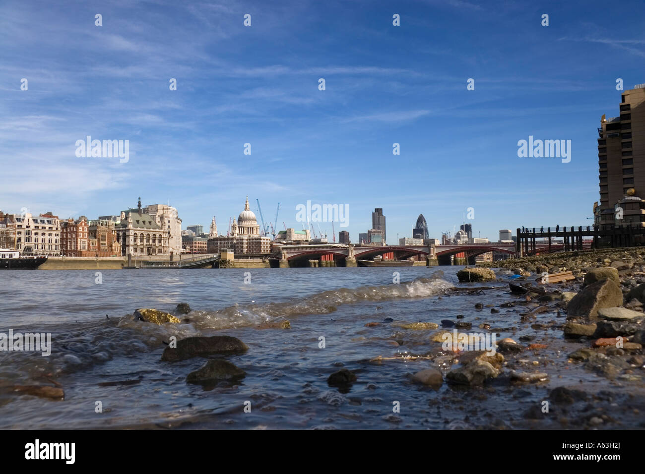 Basso angolo vista dal bordo delle acque della riva sud del fiume Tamigi guardando verso la città di Londra,UK Foto Stock
