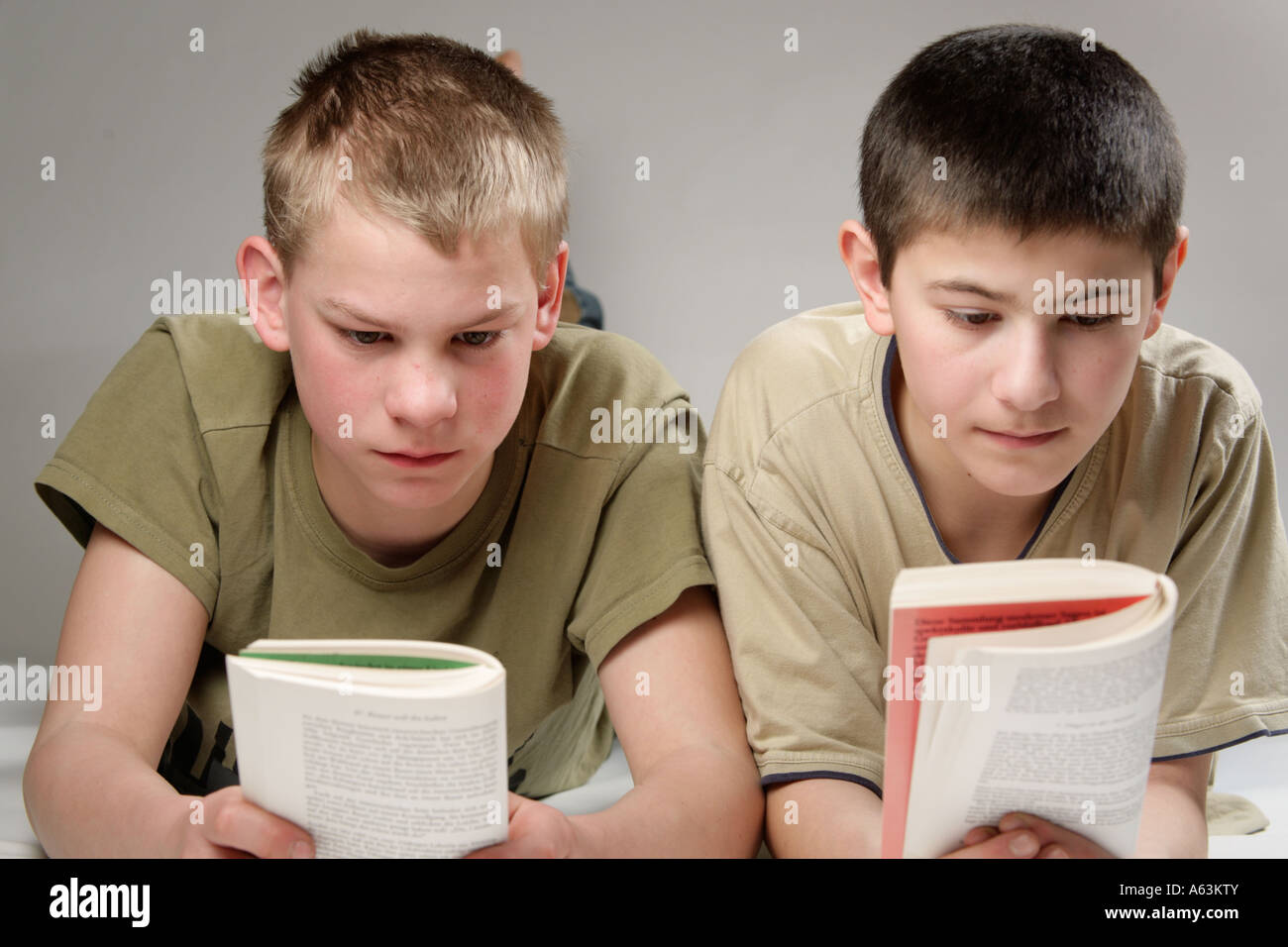 Ritratto di due giovani ragazzi giacente su un letto libri di lettura Foto Stock