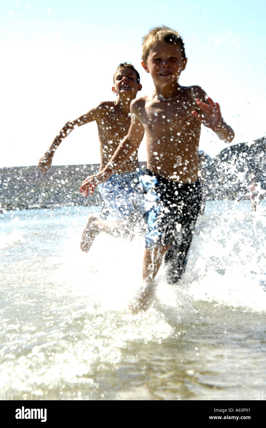 Due ragazzi giocare in acqua sulla spiaggia Foto Stock